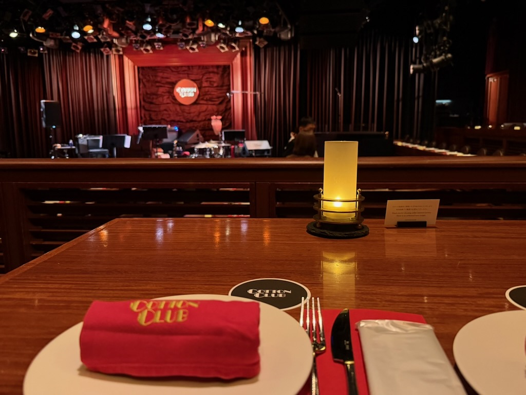 Cotton Club 開演前的座席，紅色餐巾、燭光與遠方鋪設好樂器的舞台
