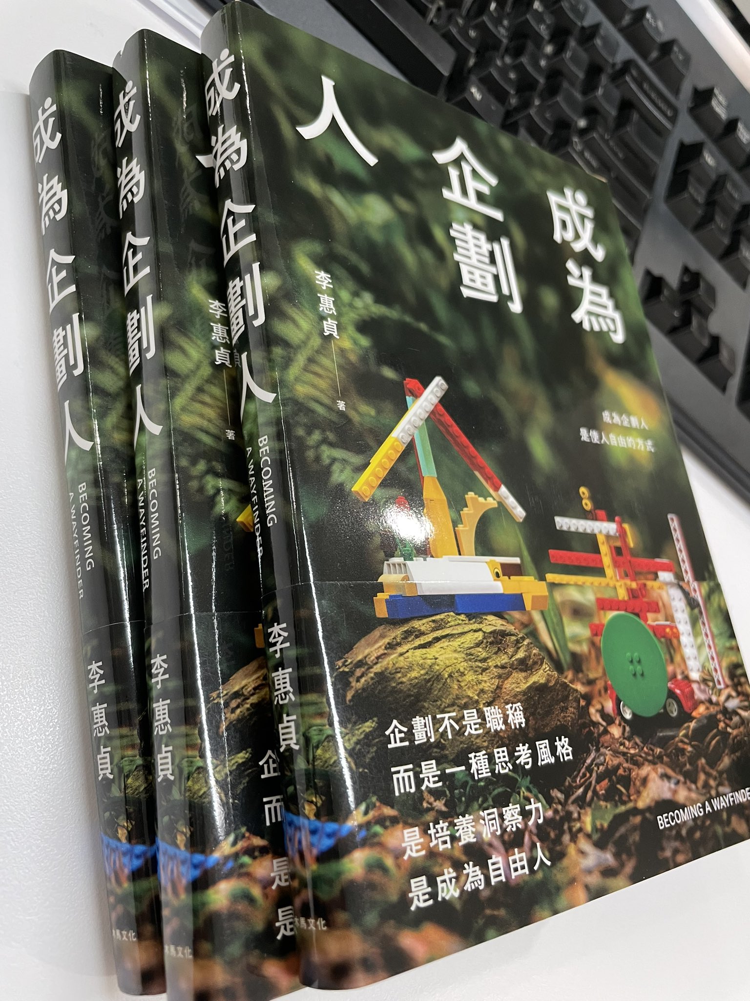 李惠貞著《成為企劃人》三本並排放在桌上，封面為樂高積木造景，英文副標「BECOMING A WAYFINDER」